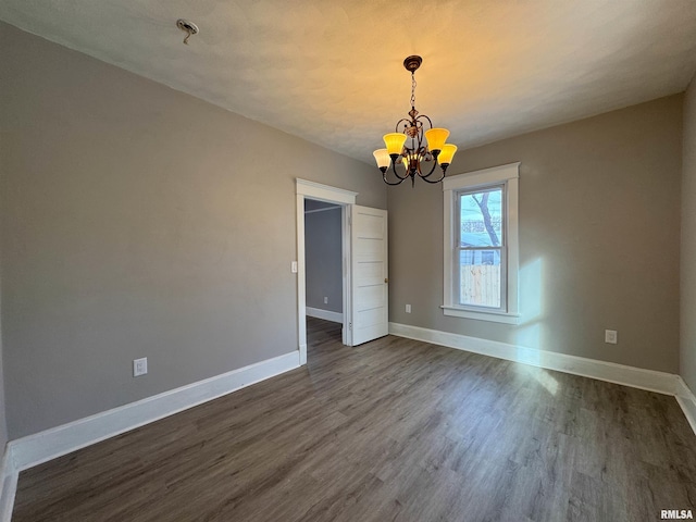 spare room featuring dark hardwood / wood-style floors and an inviting chandelier