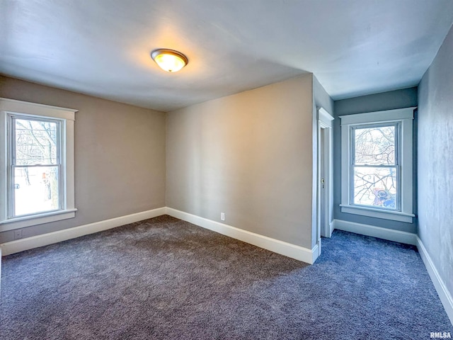 spare room featuring plenty of natural light and dark carpet