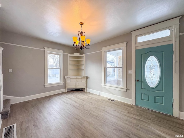 foyer entrance featuring a wealth of natural light, hardwood / wood-style floors, and a chandelier