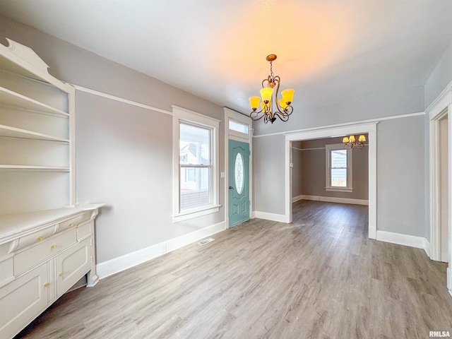 unfurnished dining area featuring light hardwood / wood-style flooring, a healthy amount of sunlight, and an inviting chandelier