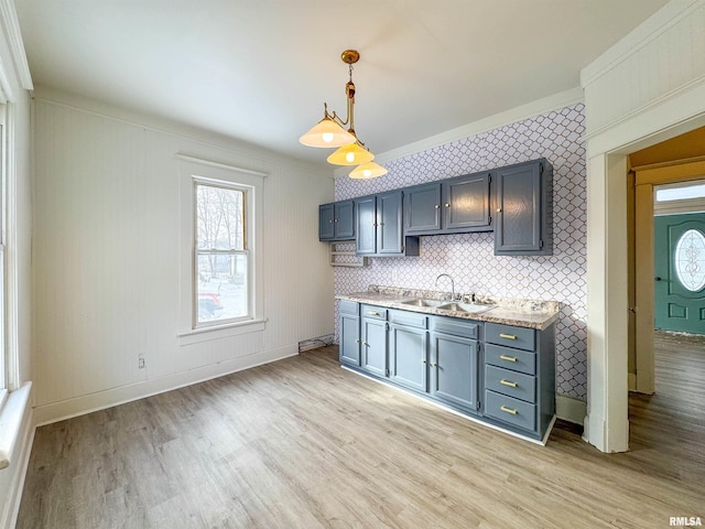 kitchen with pendant lighting, light wood-type flooring, ornamental molding, and sink