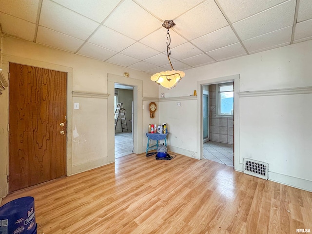 unfurnished dining area featuring hardwood / wood-style floors and a drop ceiling