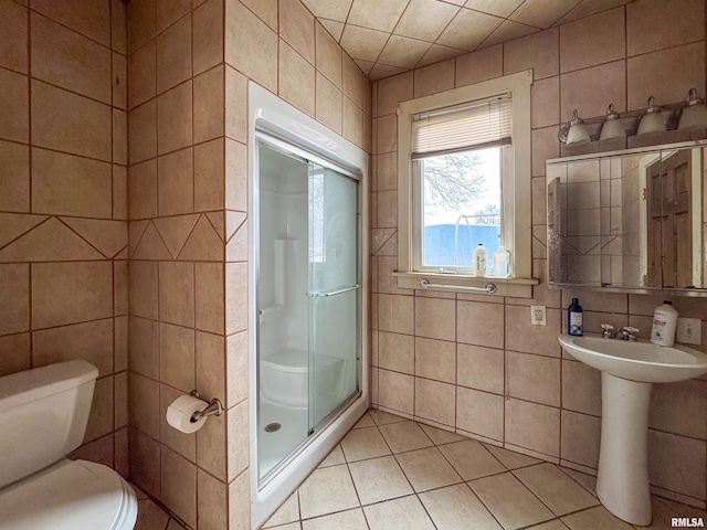 bathroom featuring tile patterned flooring, an enclosed shower, tile walls, and toilet