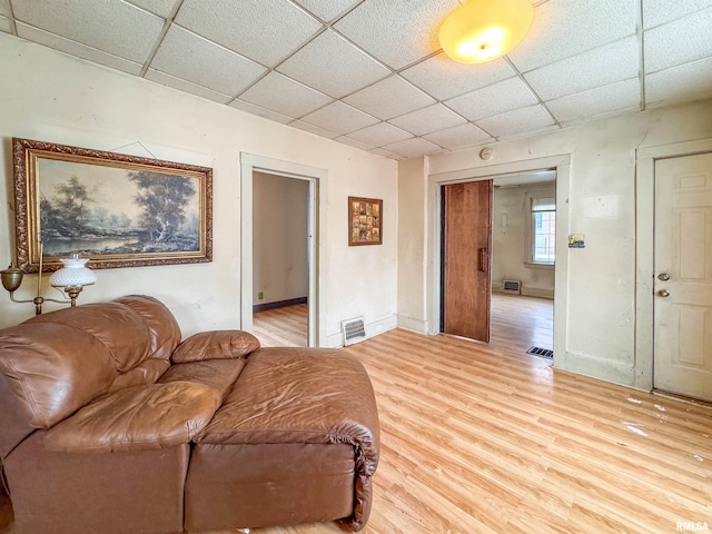 living room with a paneled ceiling and light hardwood / wood-style floors