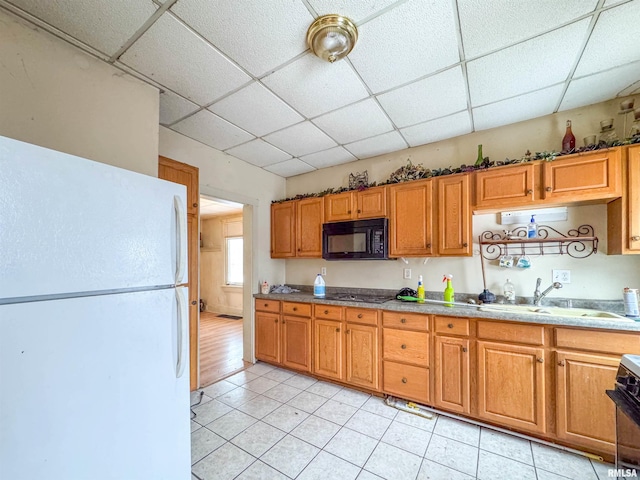 kitchen featuring black appliances, a drop ceiling, light tile patterned flooring, and sink