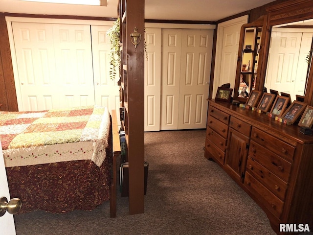 bedroom featuring multiple closets and dark colored carpet