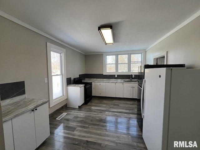 kitchen with sink, black electric range, white fridge, white cabinetry, and dark hardwood / wood-style floors