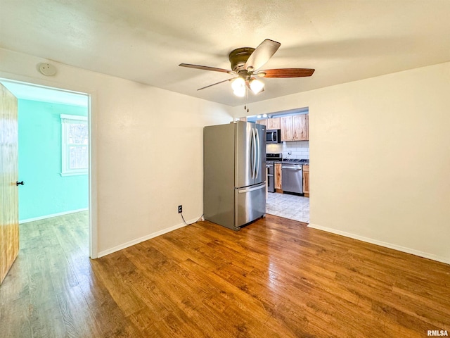 empty room with ceiling fan and light hardwood / wood-style flooring