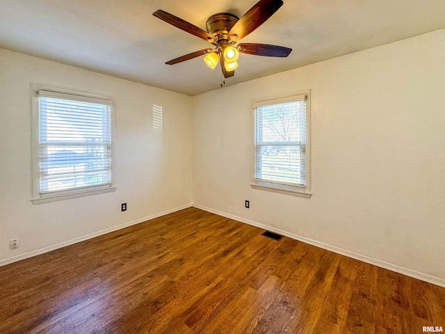 unfurnished room with dark hardwood / wood-style floors, plenty of natural light, and ceiling fan