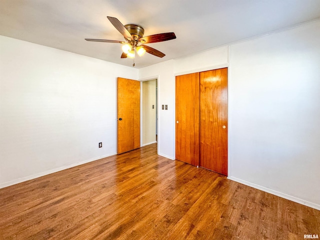 unfurnished bedroom featuring ceiling fan, a closet, and wood-type flooring