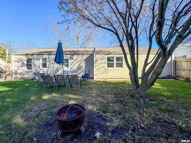 rear view of house featuring an outdoor fire pit and a lawn