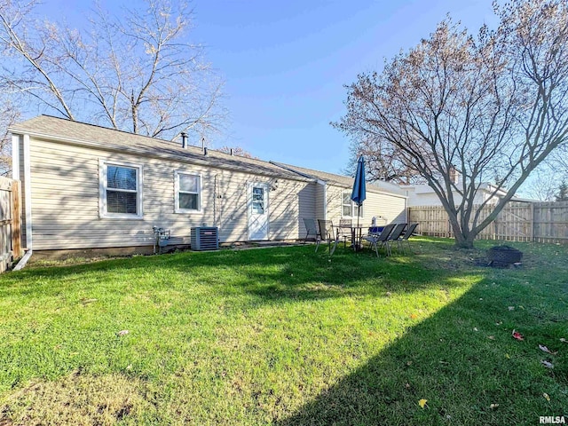 rear view of house featuring central AC unit and a yard