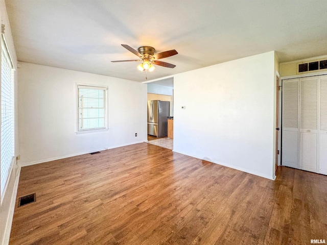 unfurnished bedroom with stainless steel refrigerator, ceiling fan, and wood-type flooring