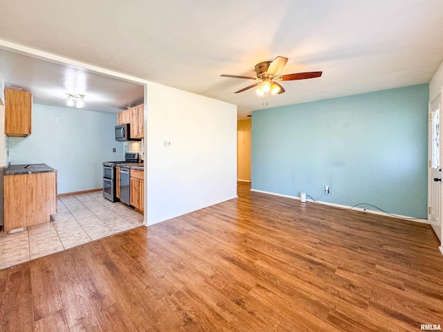 kitchen with ceiling fan, stainless steel appliances, and light wood-type flooring