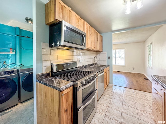 kitchen featuring sink, stainless steel appliances, decorative backsplash, light tile patterned floors, and washer and dryer