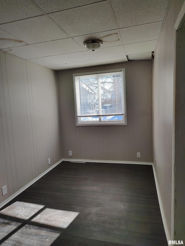 empty room featuring dark hardwood / wood-style flooring and a paneled ceiling