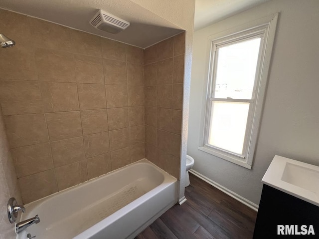 full bathroom featuring tiled shower / bath, hardwood / wood-style flooring, toilet, and a wealth of natural light