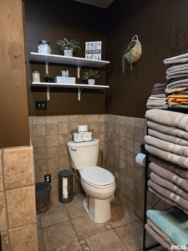 bathroom with tile patterned floors, toilet, and tile walls