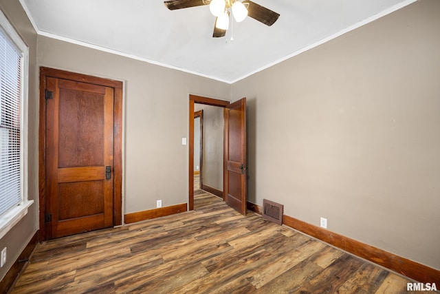 unfurnished bedroom with ceiling fan, dark hardwood / wood-style flooring, and crown molding