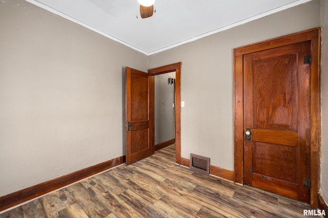 spare room with crown molding, ceiling fan, and dark wood-type flooring