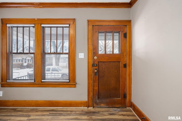 doorway with hardwood / wood-style flooring and crown molding