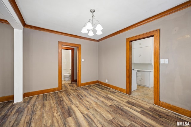 unfurnished room featuring wood-type flooring, ornamental molding, and a notable chandelier