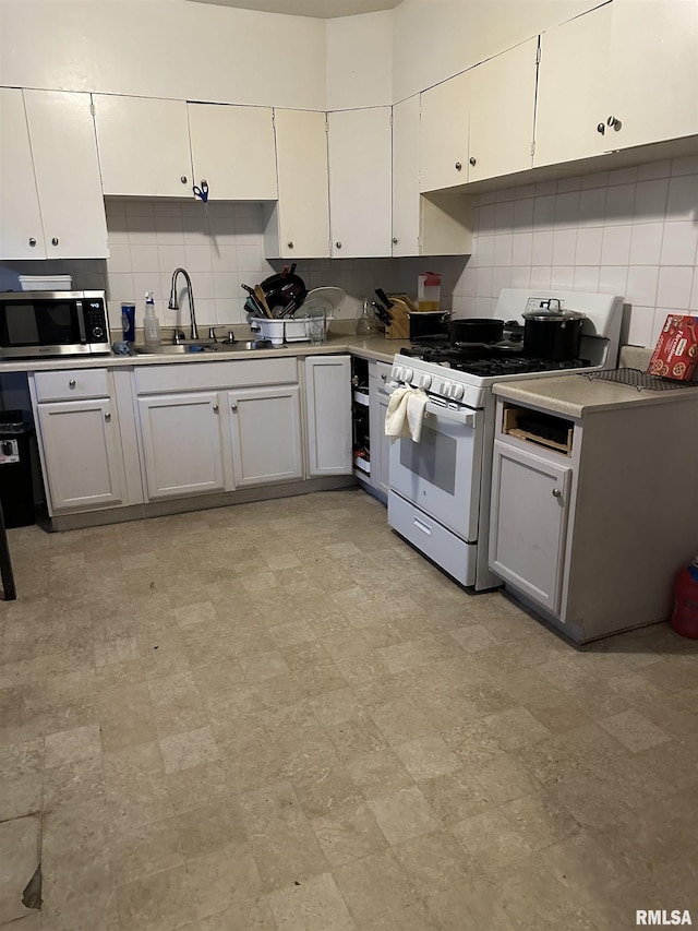 kitchen with white gas range, stainless steel microwave, light countertops, a sink, and backsplash