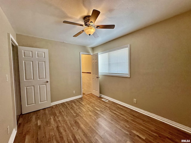 unfurnished bedroom featuring ceiling fan, wood-type flooring, and a textured ceiling