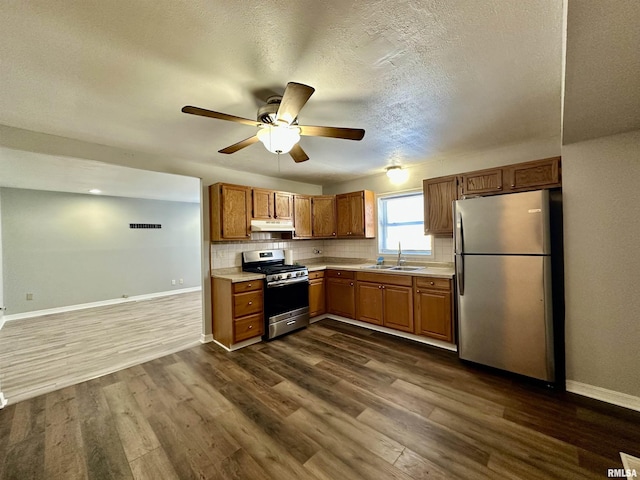 kitchen featuring dark wood-type flooring, sink, ceiling fan, tasteful backsplash, and stainless steel appliances