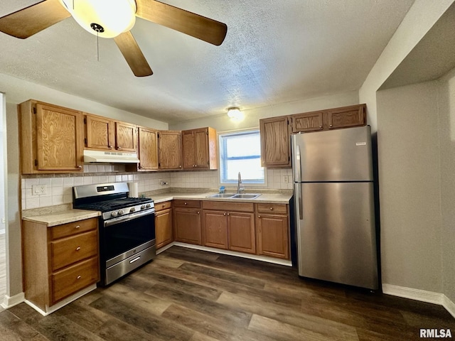 kitchen with sink, dark hardwood / wood-style floors, backsplash, a textured ceiling, and appliances with stainless steel finishes