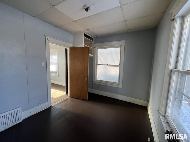 unfurnished room featuring a paneled ceiling and dark hardwood / wood-style flooring