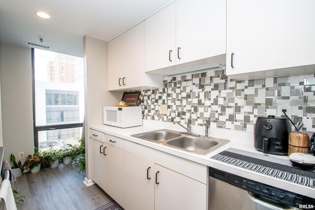 123 SW Jefferson St Unit E4W, Peoria, IL 61602 - kitchen with white microwave, stainless steel dishwasher, light countertops, wood finished floors, and tasteful backsplash