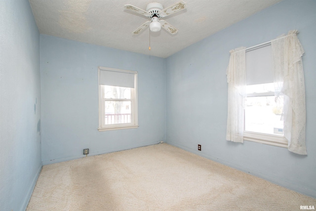 spare room with ceiling fan, light colored carpet, and a textured ceiling