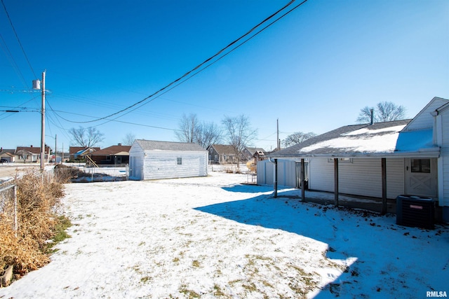 snowy yard featuring an outdoor structure and central AC unit