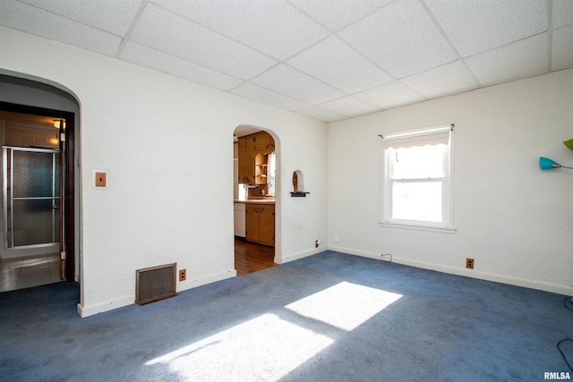 unfurnished room with a paneled ceiling and dark carpet