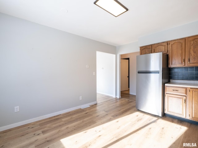 kitchen featuring decorative backsplash, light hardwood / wood-style flooring, and stainless steel refrigerator