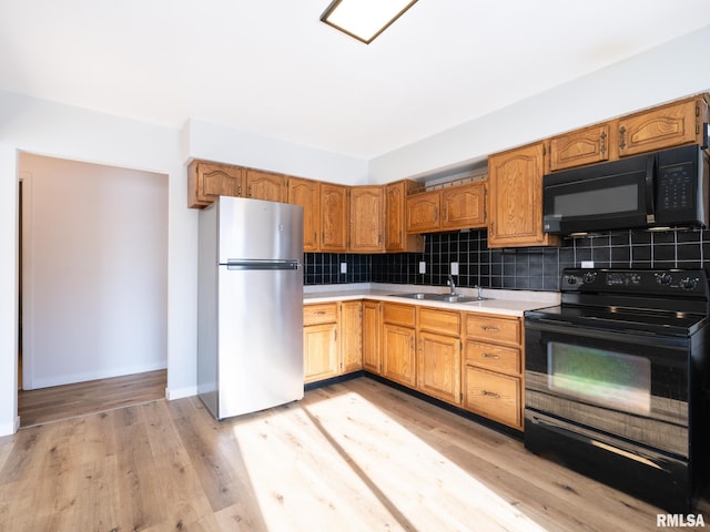 kitchen featuring backsplash, sink, black appliances, and light hardwood / wood-style floors