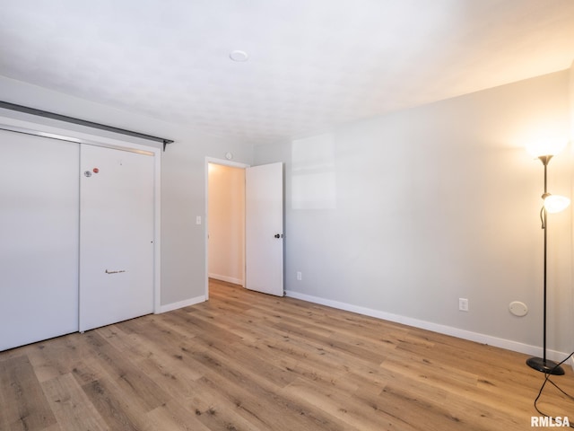 unfurnished bedroom with light wood-type flooring and a closet