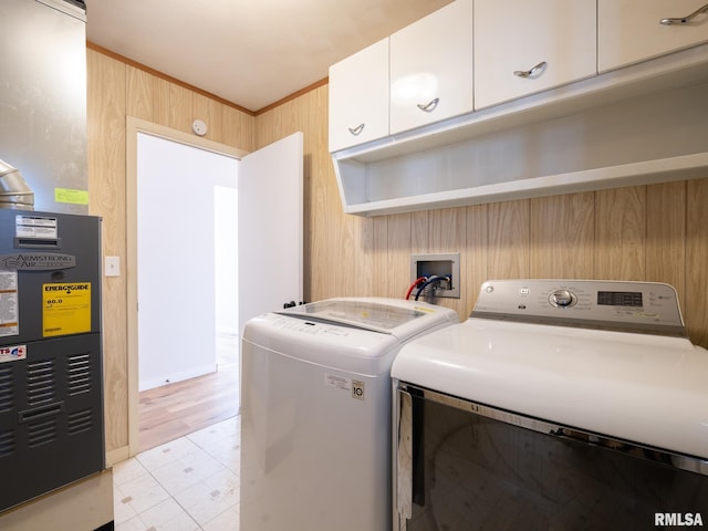 clothes washing area featuring cabinets, independent washer and dryer, wooden walls, and heating unit