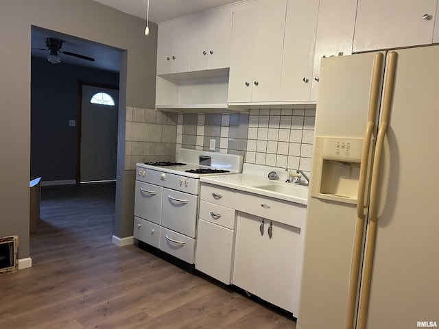 kitchen with sink, dark wood-type flooring, backsplash, white appliances, and white cabinets