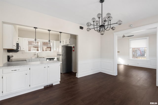 kitchen with ceiling fan with notable chandelier, stainless steel appliances, dark wood-type flooring, white cabinetry, and hanging light fixtures