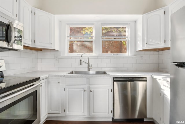 kitchen featuring white cabinets, appliances with stainless steel finishes, backsplash, and sink