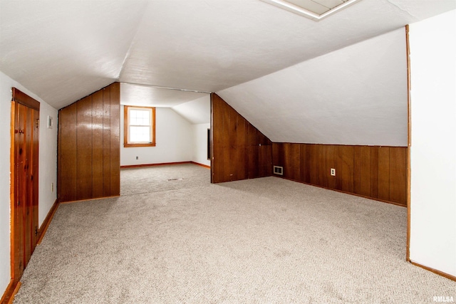 additional living space featuring light colored carpet and vaulted ceiling