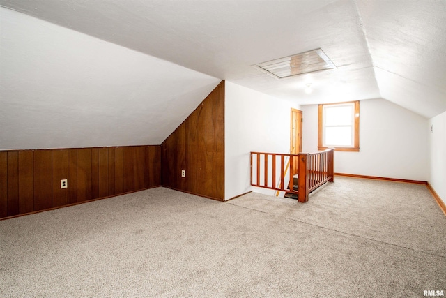 bonus room featuring wooden walls, light colored carpet, and vaulted ceiling