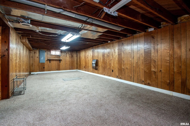 basement featuring carpet flooring, electric panel, and wood walls