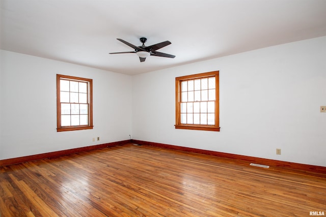 unfurnished room with hardwood / wood-style floors, a wealth of natural light, and ceiling fan