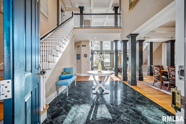 foyer featuring a high ceiling, hardwood / wood-style flooring, ornate columns, and beam ceiling