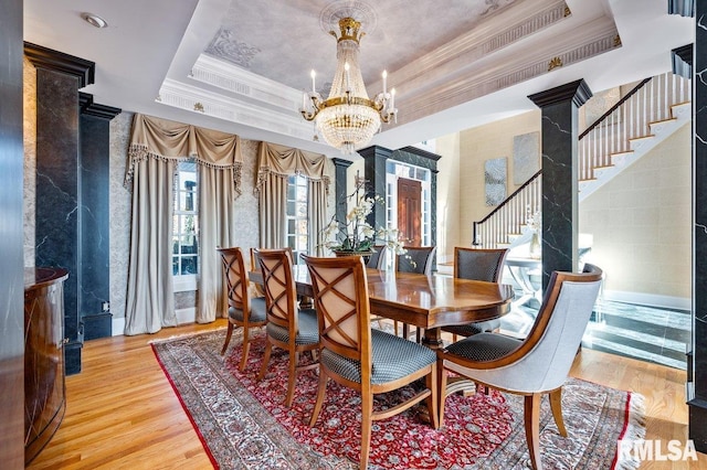 dining area with a raised ceiling, crown molding, light hardwood / wood-style floors, and a notable chandelier