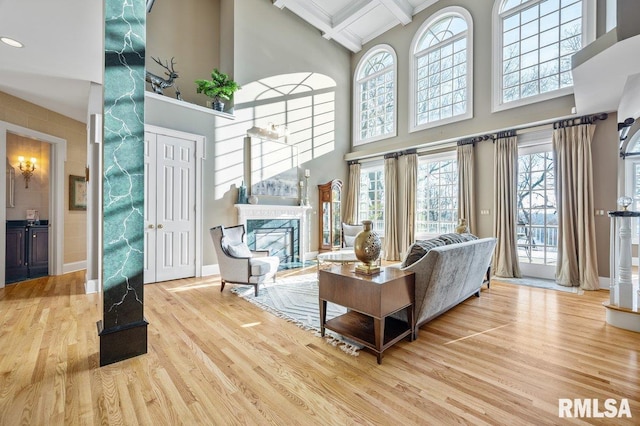 living room featuring a high end fireplace, a towering ceiling, coffered ceiling, hardwood / wood-style flooring, and beamed ceiling