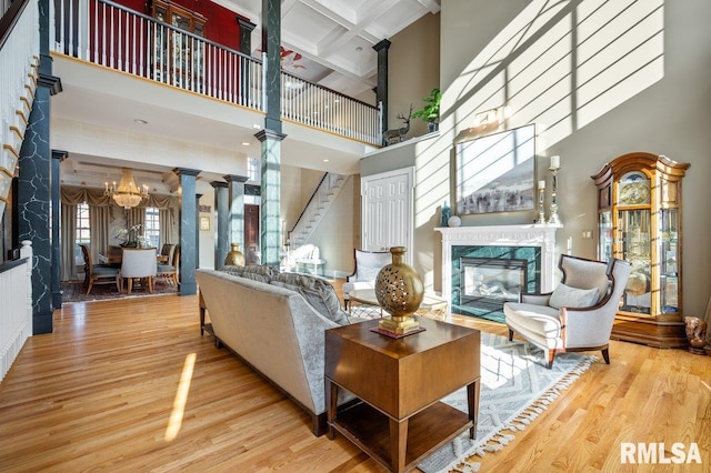 living room with coffered ceiling, hardwood / wood-style flooring, an inviting chandelier, a premium fireplace, and a high ceiling